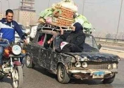 صورة لسيدة تجلس على سيارة متهالكة تحمل بضاعتها