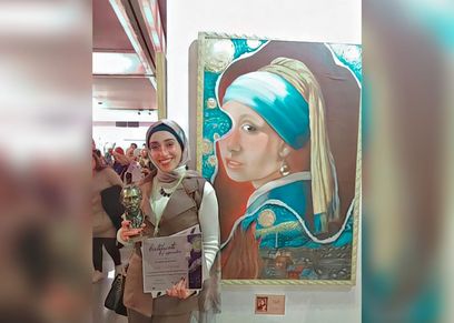 مريم حمزة مع إحدى لوحاتها الفنية