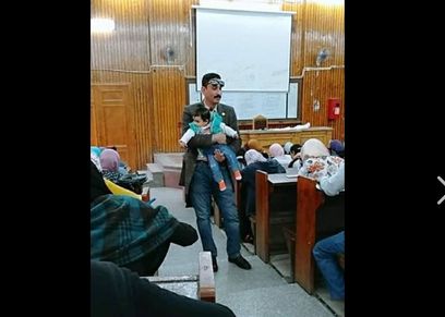 الأستاذ الجامعي يحمل الرضيعة