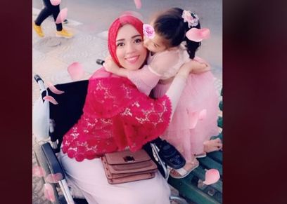 منى على الكرسي المتحرك برفقة طفلتها