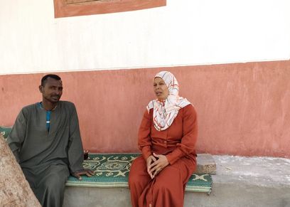 عزيزة أدم تستمع إلى أحد أهالي القرية