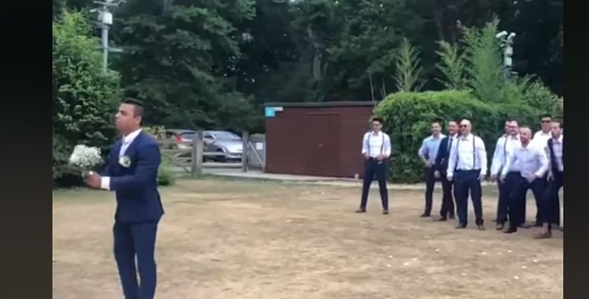 مقطع فيديو ساخر لرجل يمسك بالزهور ويلقيها على اصدقائه اثناء عرسه