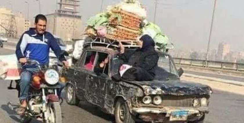 صورة لسيدة تجلس على سيارة متهالكة تحمل بضاعتها