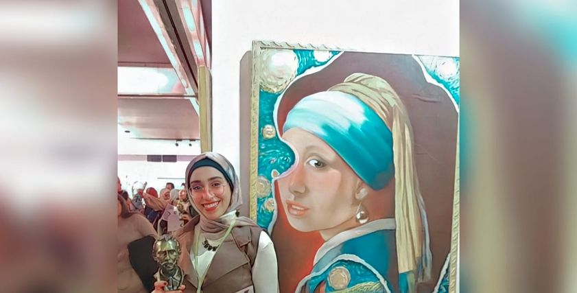 مريم حمزة مع إحدى لوحاتها الفنية
