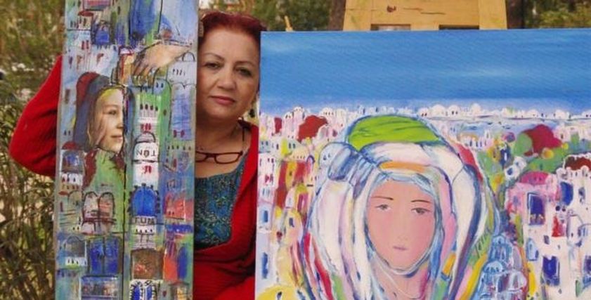 الفنانة التشكيلية السورية عتاب حريب وسط لوحاتها