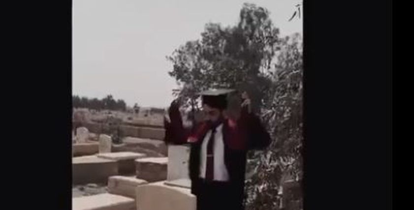 شاب يحتفل بتخرجه عند قبر أمه
