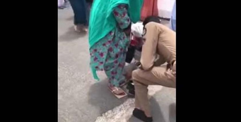 رجل أمن يخلع حذاءه لامرأة مسنة ليقيها من حرارة الأرض