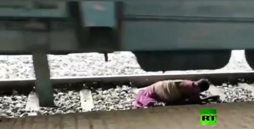 بالفيديو ..عجوز هندية تستلقى بين عجلات القطار أثناء عبور القضبان